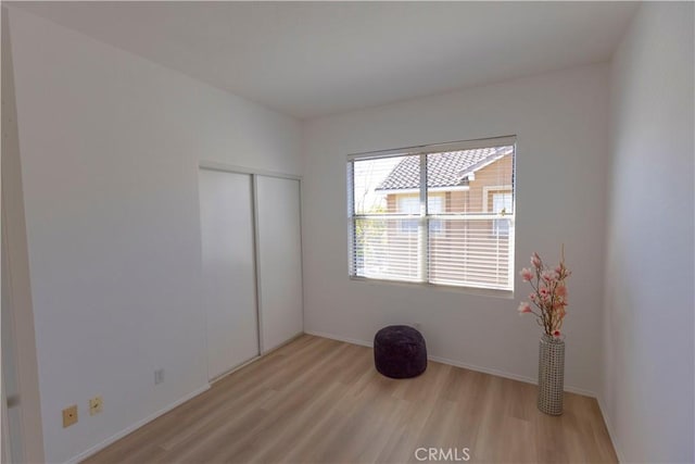 unfurnished bedroom with light wood finished floors, a closet, and baseboards