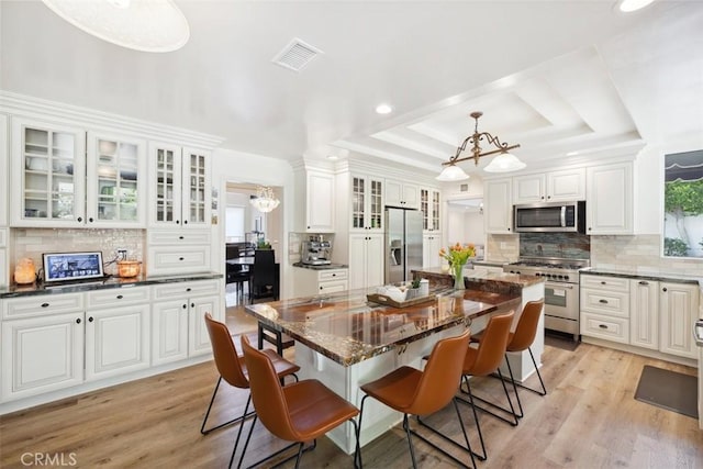 dining room featuring a chandelier, a tray ceiling, visible vents, and light wood-style floors