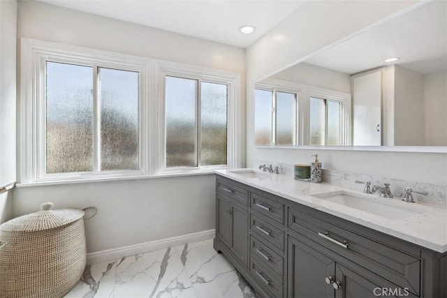 full bath with marble finish floor, a sink, baseboards, and double vanity