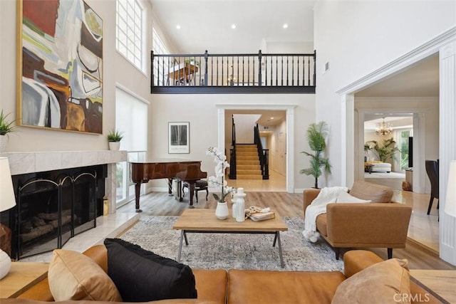 living area with an inviting chandelier, stairs, a towering ceiling, wood finished floors, and a fireplace