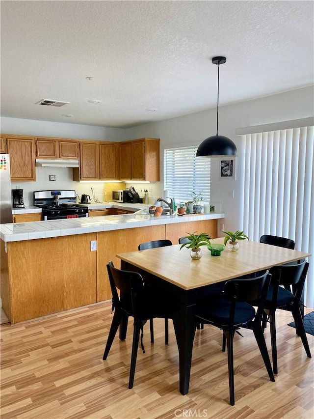 dining room with light wood-style floors, visible vents, and a textured ceiling