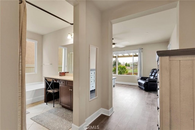 hallway featuring light wood finished floors and baseboards