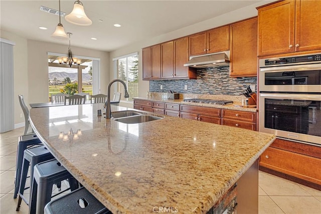 kitchen with under cabinet range hood, stainless steel appliances, a sink, and light tile patterned flooring