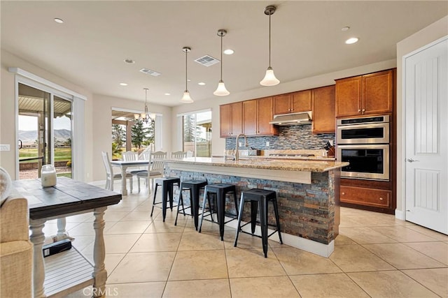 kitchen with double oven, light tile patterned flooring, visible vents, and under cabinet range hood