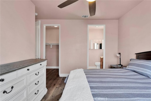 bedroom featuring dark wood-type flooring, visible vents, baseboards, a closet, and a walk in closet