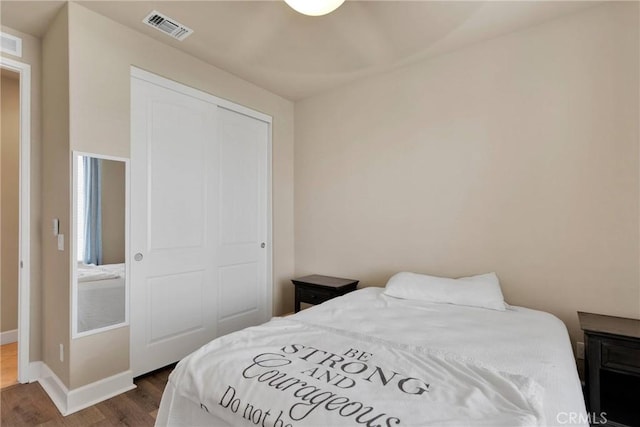 bedroom featuring a closet, visible vents, baseboards, and wood finished floors