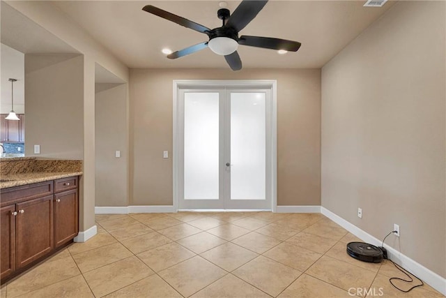 interior space featuring light tile patterned floors, baseboards, a ceiling fan, and french doors