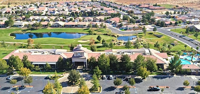 drone / aerial view with a residential view, view of golf course, and a water view