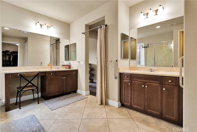 bathroom with a stall shower, vanity, baseboards, and tile patterned floors