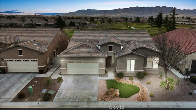 view of front facade featuring a garage, driveway, a mountain view, and stucco siding