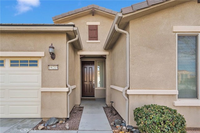 property entrance with a garage and stucco siding