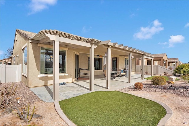 rear view of property featuring fence, a ceiling fan, stucco siding, a pergola, and a patio area