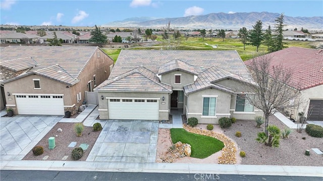 view of front of property featuring a garage, a mountain view, concrete driveway, and stucco siding