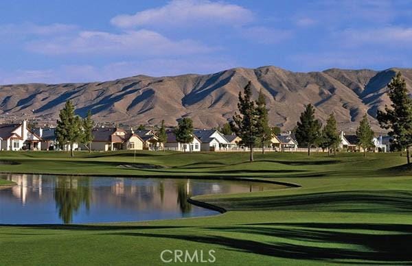 view of community featuring view of golf course, a lawn, a residential view, and a water and mountain view