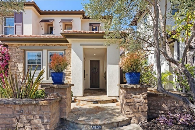 view of front facade with stone siding, a tile roof, and stucco siding