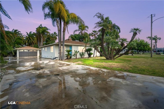 view of front of home with a detached garage, a front lawn, and an outbuilding