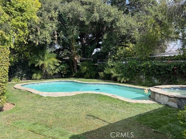 view of pool with a pool with connected hot tub and a yard