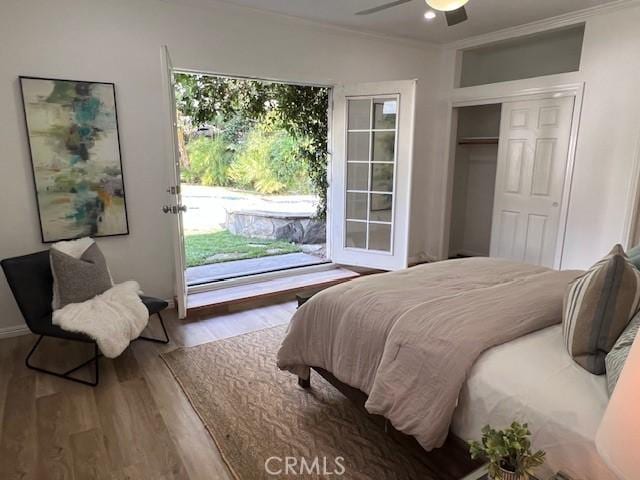 bedroom featuring access to outside, a closet, crown molding, and wood finished floors