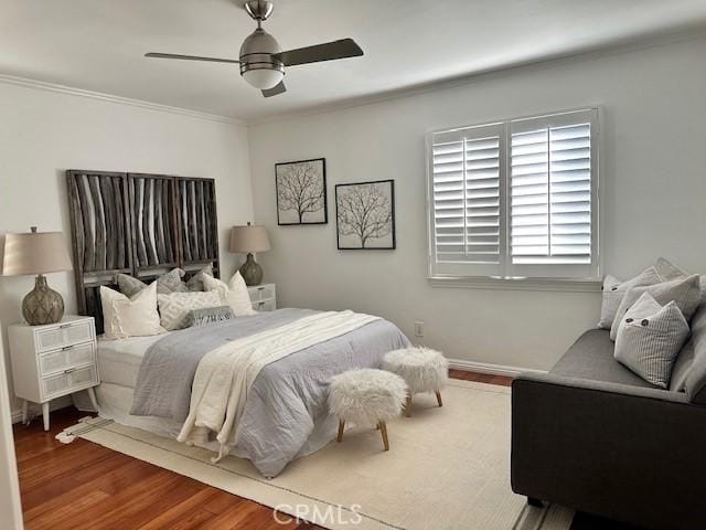 bedroom with ornamental molding, ceiling fan, baseboards, and wood finished floors