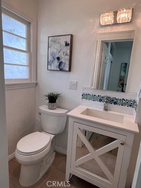 bathroom featuring baseboards, vanity, and toilet