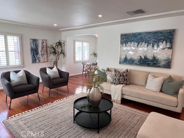 living room with baseboards, visible vents, wood finished floors, and recessed lighting