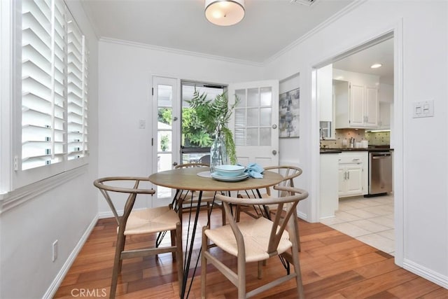 dining area with light wood-style floors, baseboards, and ornamental molding