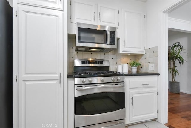 kitchen with appliances with stainless steel finishes, white cabinetry, and tasteful backsplash