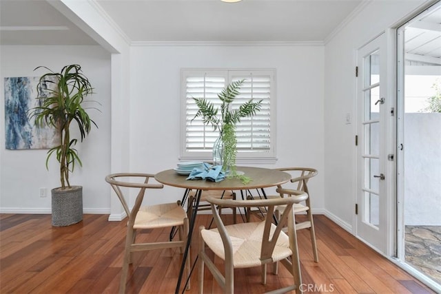 dining space with ornamental molding, baseboards, and wood finished floors