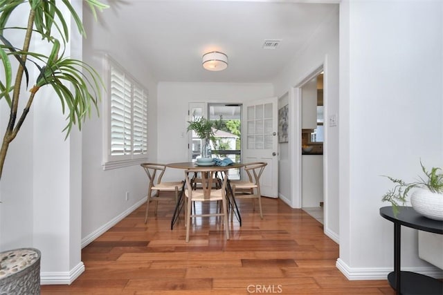 dining area featuring light wood finished floors, baseboards, and visible vents