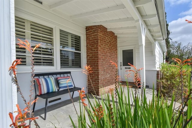 property entrance with covered porch and brick siding