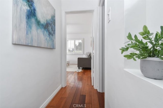 corridor featuring wood-type flooring and baseboards