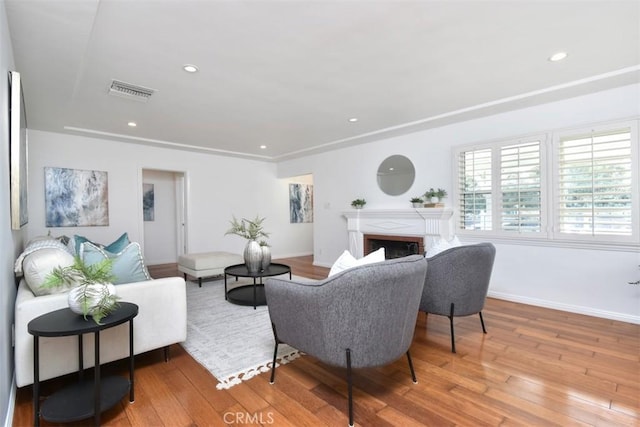 living area featuring recessed lighting, a fireplace, visible vents, baseboards, and hardwood / wood-style floors