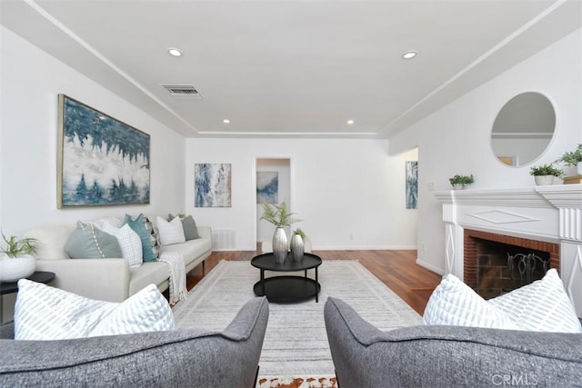 living area with baseboards, visible vents, wood finished floors, a fireplace, and recessed lighting