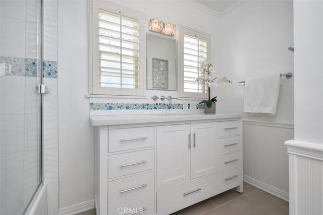 bathroom featuring a wainscoted wall, crown molding, bath / shower combo with glass door, vanity, and tile patterned floors