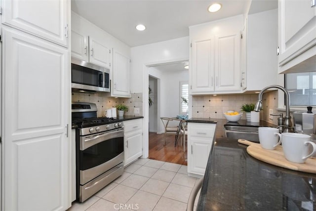 kitchen with appliances with stainless steel finishes, plenty of natural light, a sink, and white cabinetry