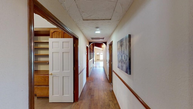 hallway with arched walkways and wood finished floors