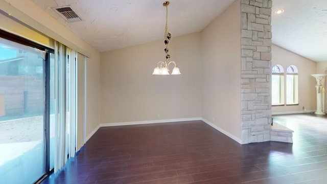 spare room with visible vents, wood finished floors, an inviting chandelier, vaulted ceiling, and ornate columns