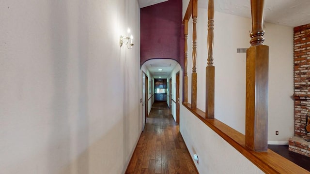 hall featuring arched walkways, hardwood / wood-style flooring, and baseboards