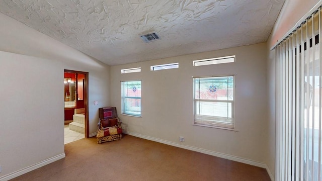 spare room featuring baseboards, visible vents, light colored carpet, lofted ceiling, and a textured ceiling