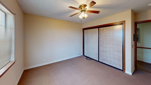 unfurnished bedroom with a closet, carpet flooring, a ceiling fan, and baseboards