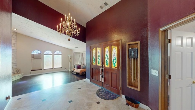 foyer entrance with baseboards, visible vents, a chandelier, wood finished floors, and high vaulted ceiling