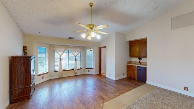 interior space with lofted ceiling, a ceiling fan, visible vents, and wood finished floors