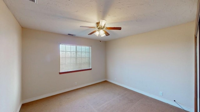 empty room with light carpet, baseboards, visible vents, and ceiling fan