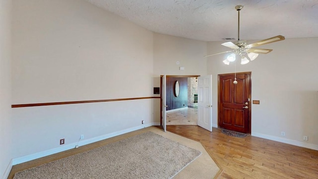 entryway with visible vents, baseboards, wood finished floors, vaulted ceiling, and a textured ceiling