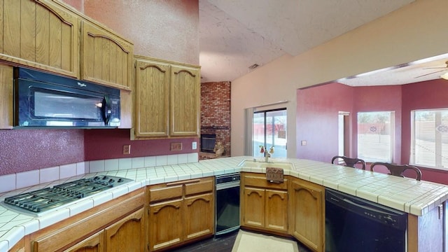 kitchen with a ceiling fan, a peninsula, a textured ceiling, black appliances, and a sink