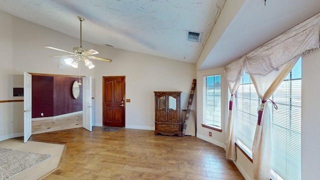 interior space with lofted ceiling, visible vents, light wood-style floors, ceiling fan, and baseboards