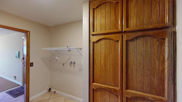 laundry area with hookup for a washing machine, cabinet space, baseboards, and light tile patterned floors