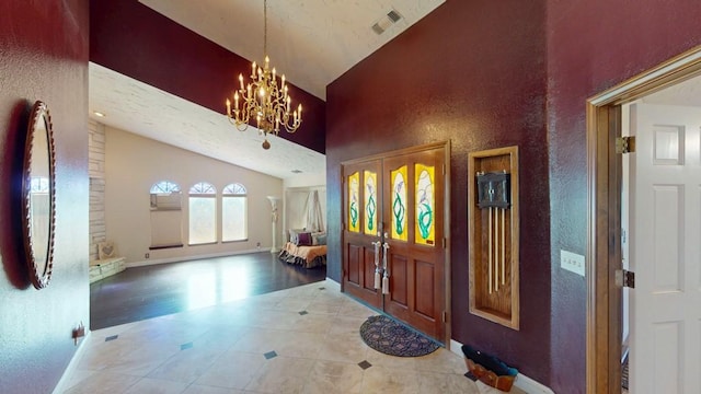 entryway featuring a textured wall, high vaulted ceiling, a notable chandelier, visible vents, and baseboards