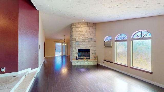 unfurnished living room featuring a stone fireplace, baseboards, and wood finished floors