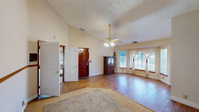 interior space featuring a textured ceiling, wood finished floors, visible vents, baseboards, and a ceiling fan